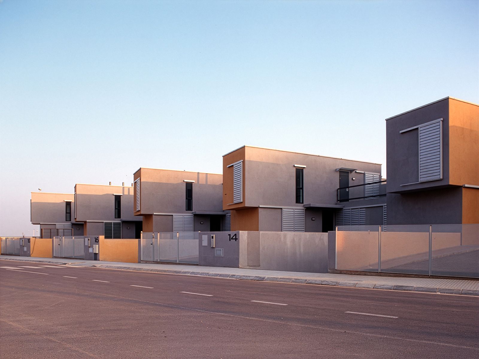 Una hilera de casas modernas de dos pisos con líneas limpias y diseño minimalista, con grandes ventanas y una paleta de colores neutros.