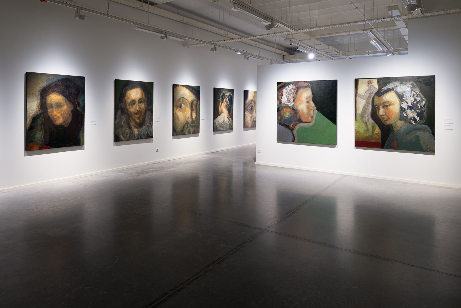 Galería de arte con retratos de Guerrero Medina exhibidos en paredes blancas y suelos de hormigón pulido.