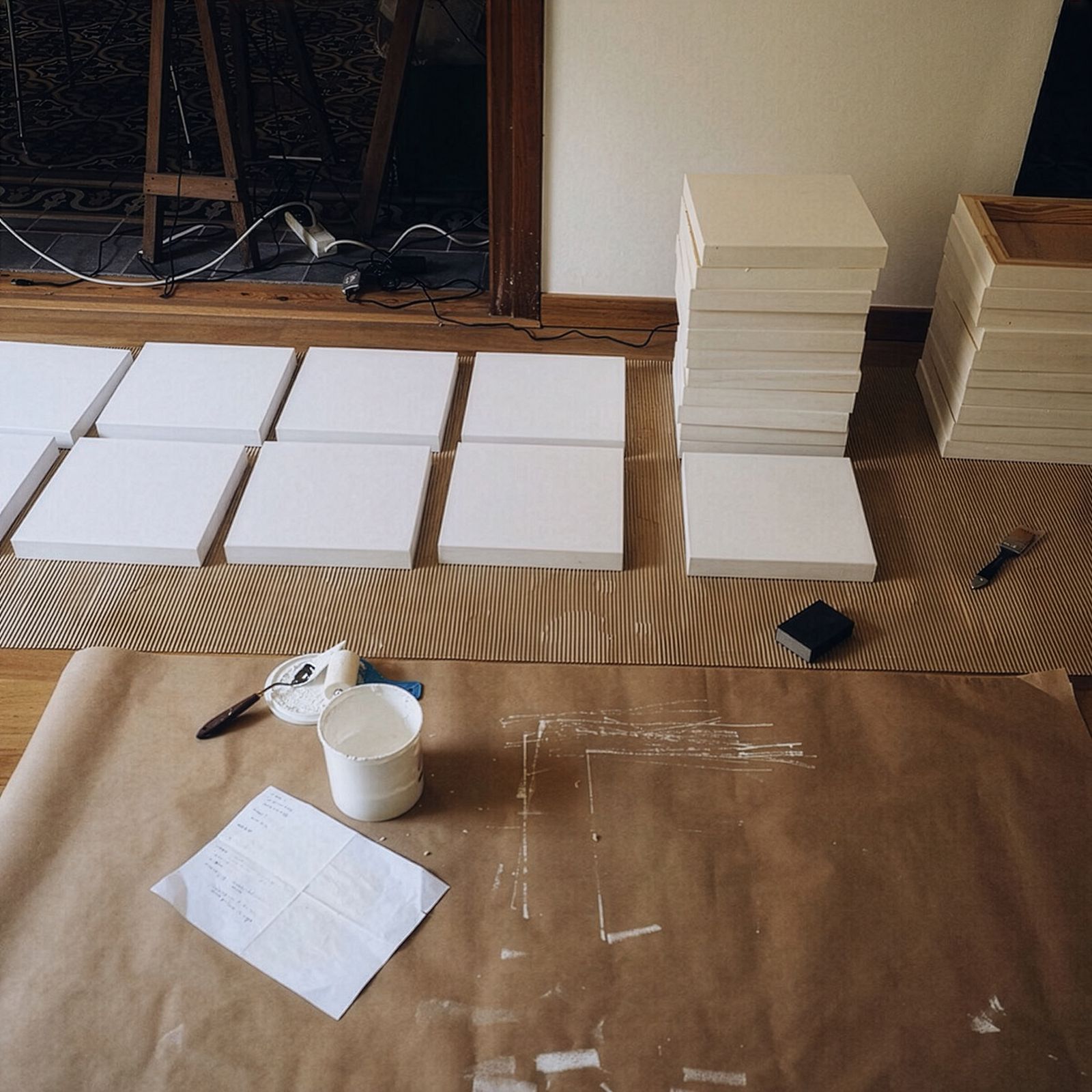 Material de arte, lienzos en blanco y pilas de marcos dispuestos en el suelo, listos para preparación en el espacio de trabajo de un artista.