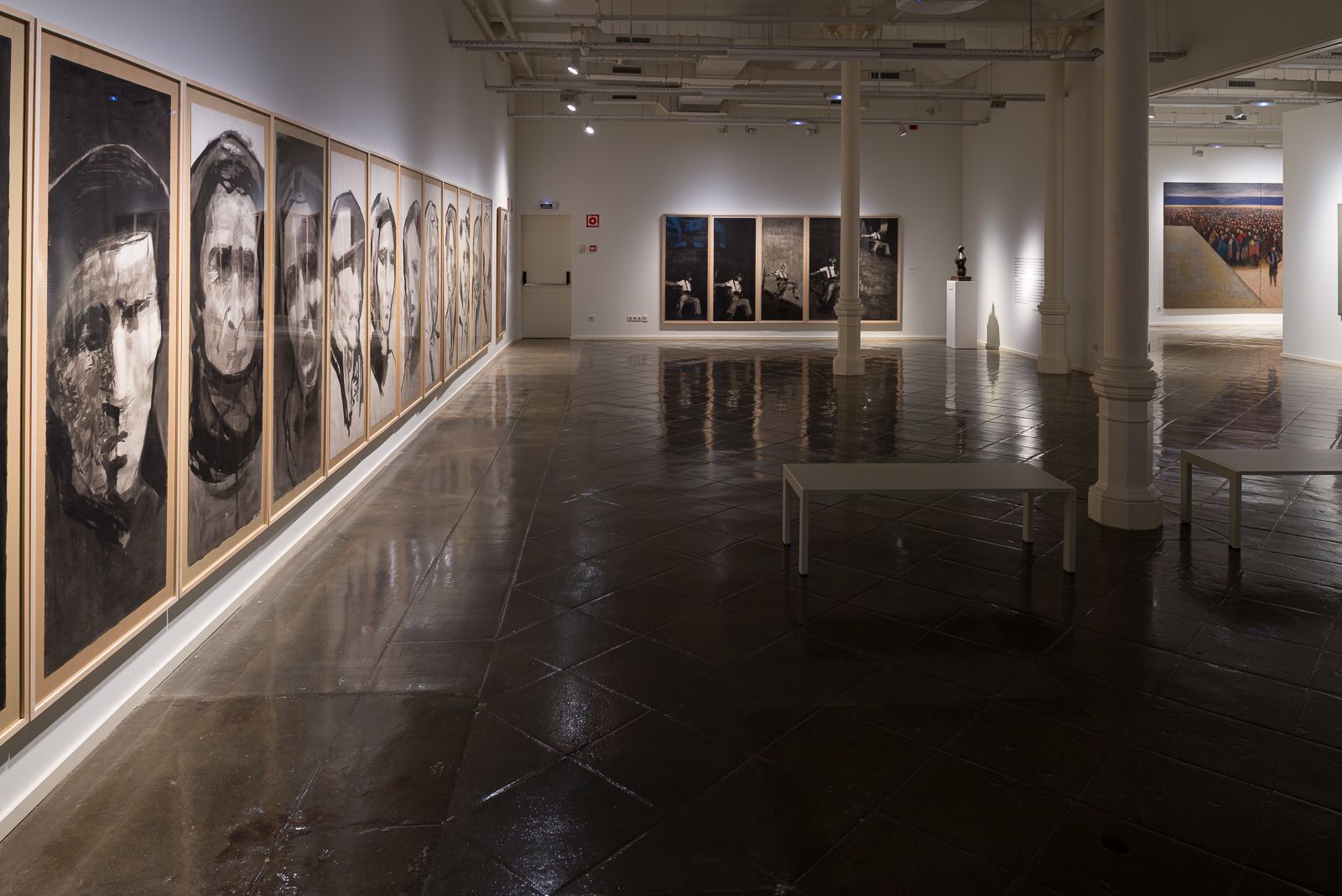 Galería de arte con una serie de grandes pinturas de retratos a la izquierda y obras adicionales al fondo.