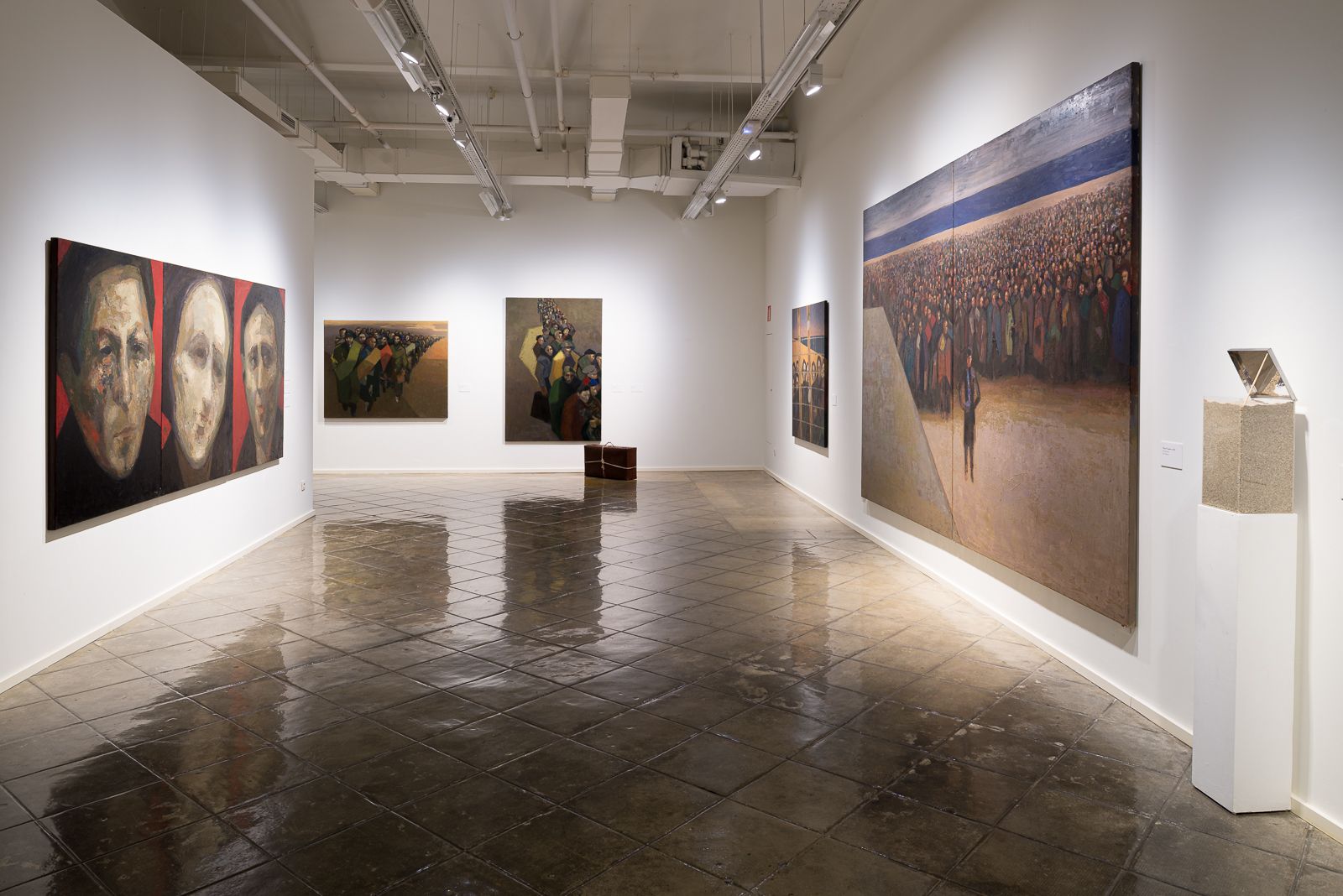 Galería de arte con pinturas de Guerrero Medina, con retratos a la izquierda y grandes escenas de multitudes a la derecha.