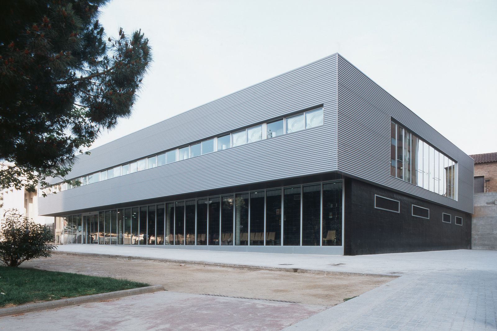 Un exterior de clínica médica moderna con grandes ventanas y elegantes paneles metálicos horizontales.