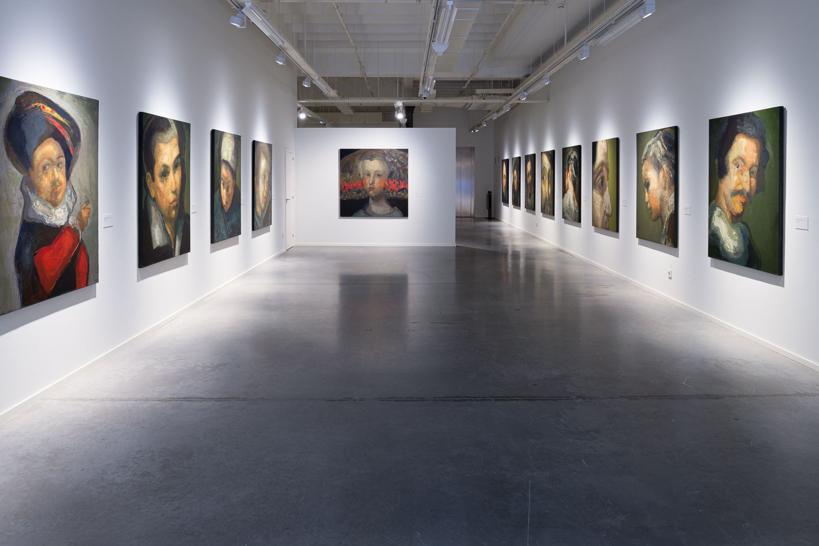 Sala de exposición con grandes retratos de Guerrero Medina, paredes blancas y suelo de hormigón pulido.