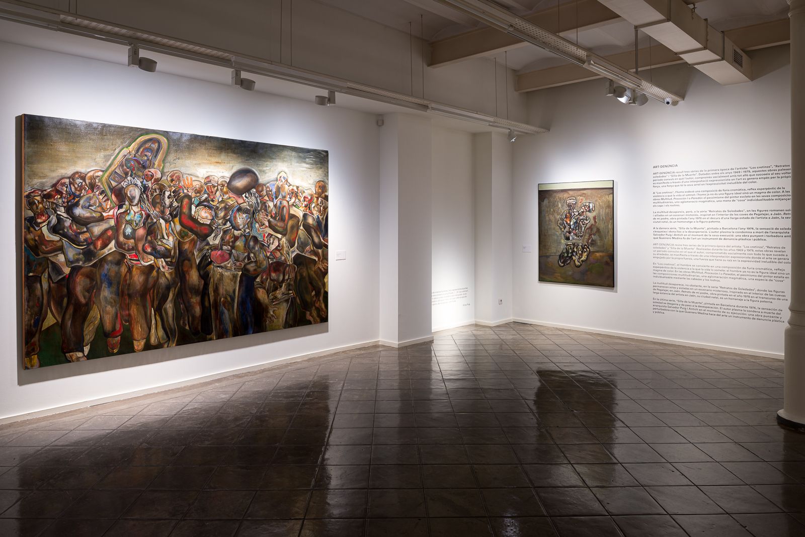 Una galería que muestra grandes pinturas vibrantes con escenas de grupo dinámicas en paredes blancas, acompañadas de texto descriptivo.