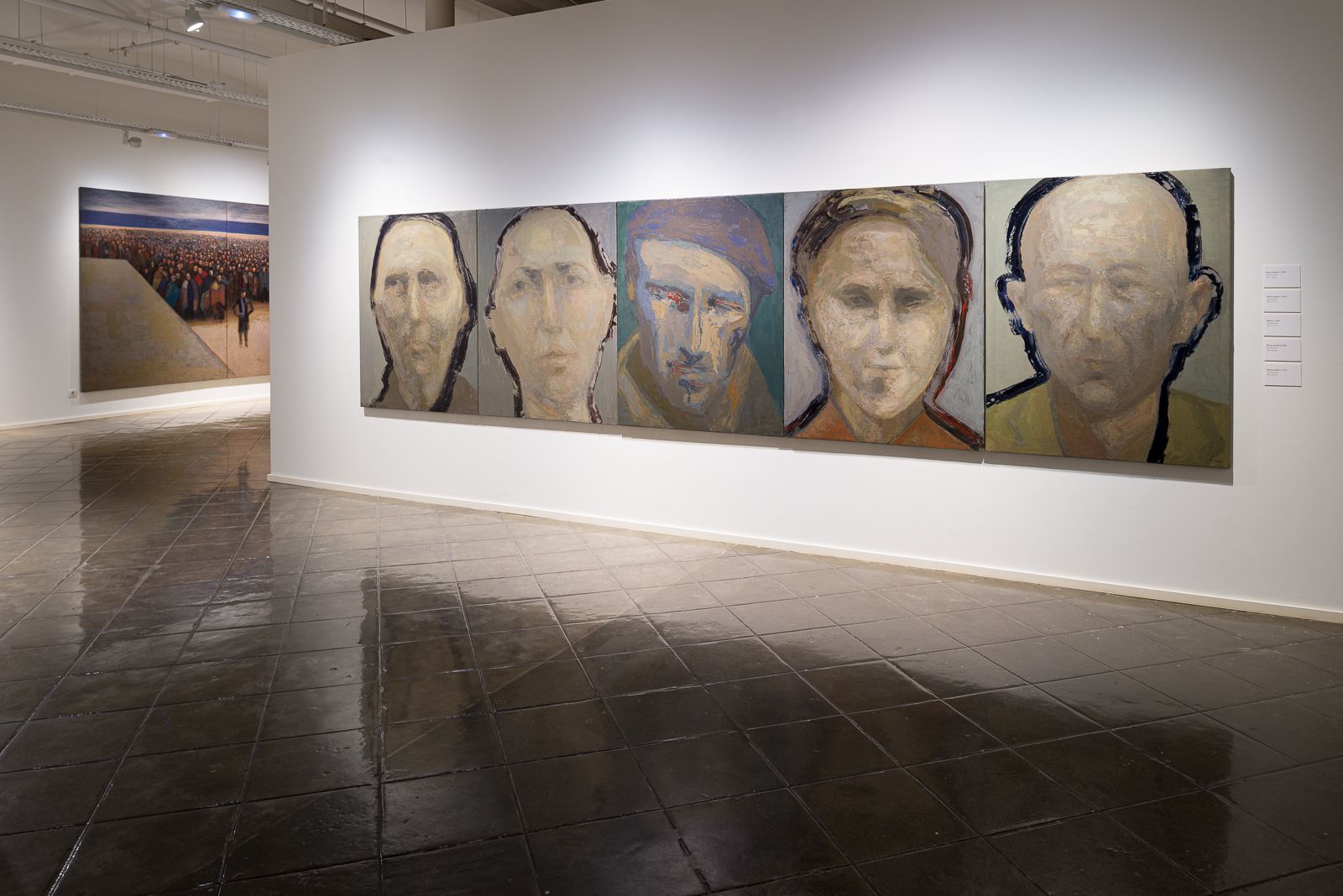 Galería que muestra cinco grandes pinturas de retratos en fila en la pared derecha y una gran pintura mural al fondo.