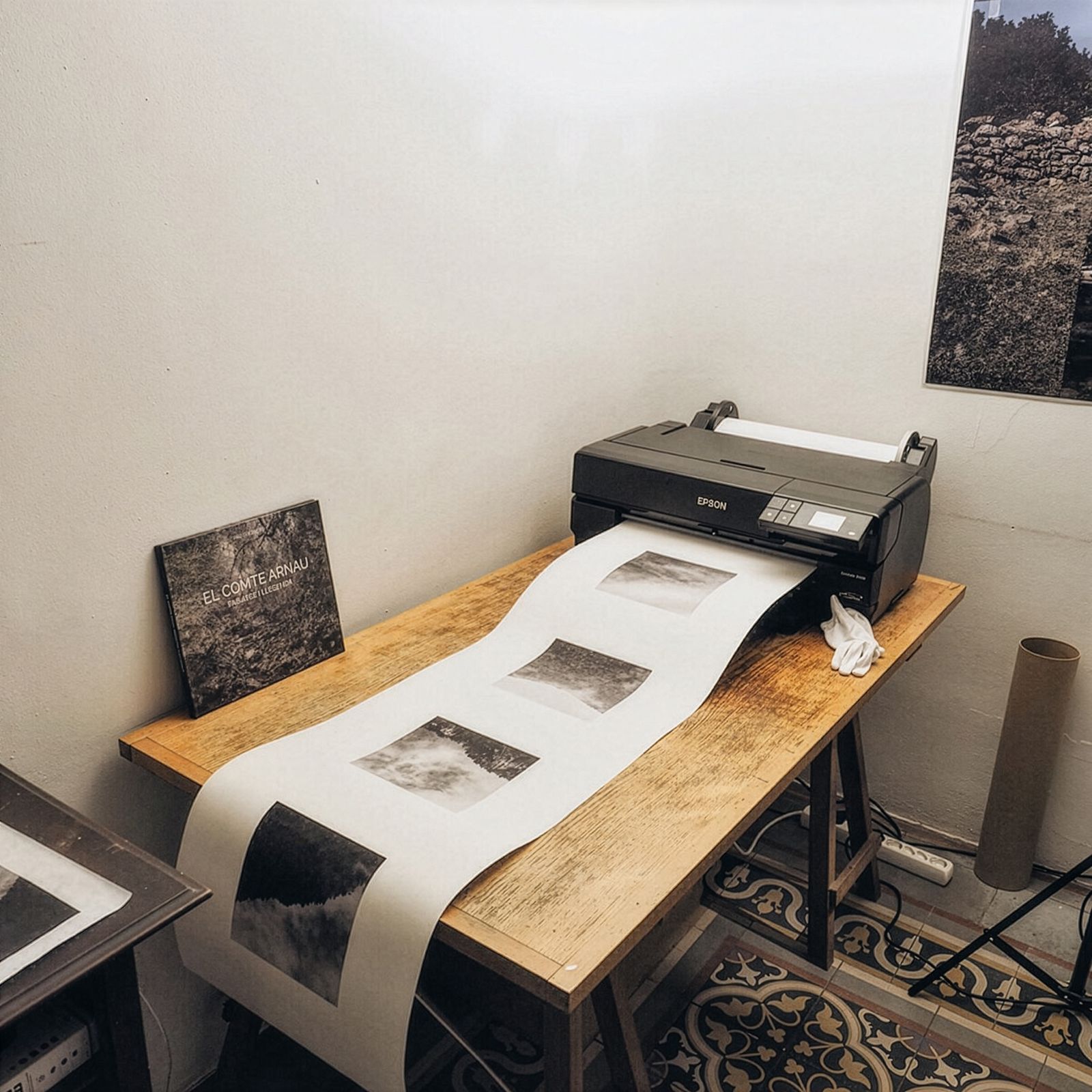 Una impresora sobre una mesa de madera produciendo una larga tira de fotografías en blanco y negro.